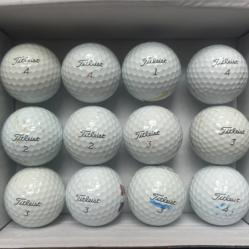 A dozen Grade B Titleist golf balls, some marks and discolouration